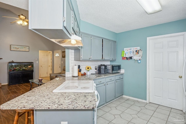 kitchen featuring a textured ceiling, kitchen peninsula, and ceiling fan