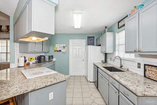 kitchen featuring stainless steel appliances, sink, decorative backsplash, a textured ceiling, and light tile patterned flooring