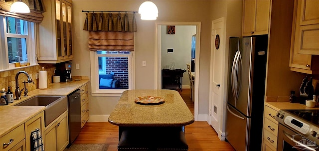 kitchen with a kitchen island, pendant lighting, stainless steel appliances, a wealth of natural light, and light wood-type flooring