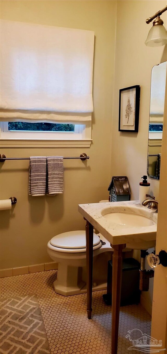 bathroom with toilet, sink, and tile patterned floors