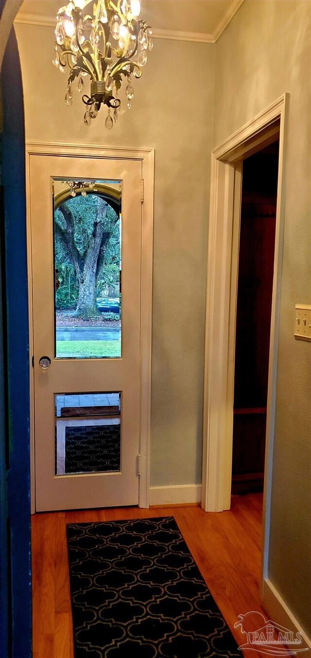 entrance foyer featuring crown molding, hardwood / wood-style floors, and a notable chandelier