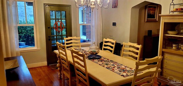 dining space featuring dark wood-type flooring and an inviting chandelier