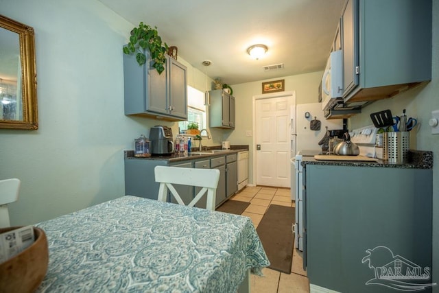 8687 John Hamm Rd, Milton, FL 32583 - kitchen featuring white microwave, light tile patterned floors, dark countertops, and a sink