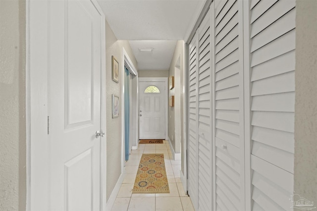 hallway with light tile patterned floors and baseboards