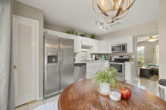 kitchen with visible vents, light tile patterned floors, stainless steel appliances, white cabinetry, and a sink