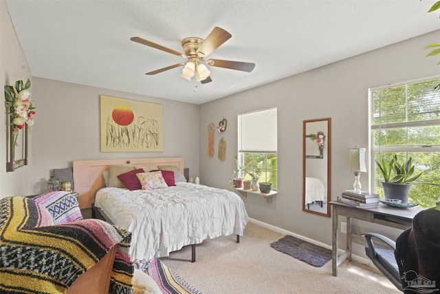 carpeted bedroom with multiple windows, a ceiling fan, and baseboards