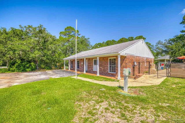 view of front of home featuring brick siding, a front lawn, fence, driveway, and a gate