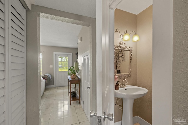 bathroom featuring tile patterned floors, a textured wall, and a textured ceiling