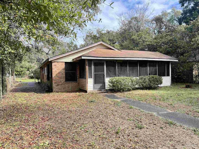 view of front of property with a sunroom, brick siding, and fence