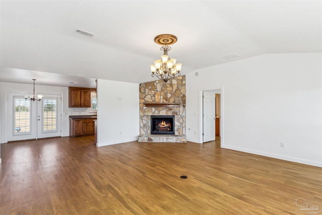 unfurnished living room with a chandelier, a fireplace, hardwood / wood-style floors, and lofted ceiling