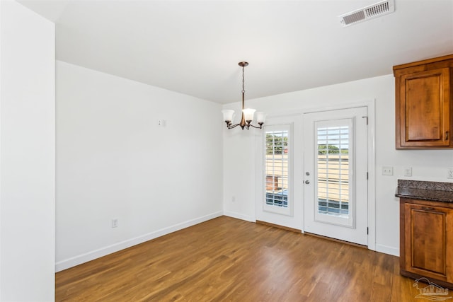 unfurnished dining area with dark hardwood / wood-style flooring, french doors, and an inviting chandelier