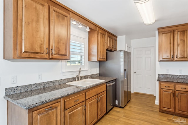 kitchen featuring dishwasher, sink, dark stone counters, and light hardwood / wood-style flooring