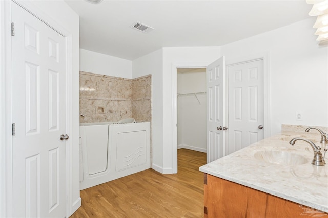 bathroom featuring hardwood / wood-style floors, vanity, and a bath