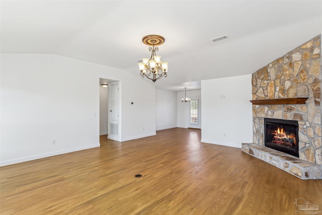 unfurnished living room featuring a fireplace, a chandelier, lofted ceiling, and wood-type flooring