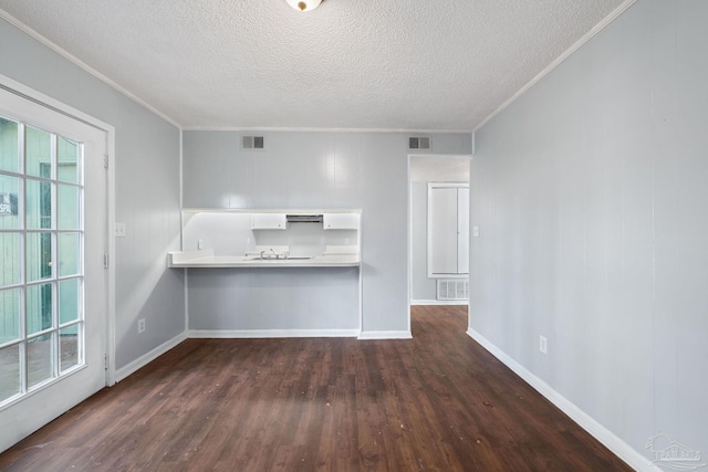 unfurnished living room featuring a textured ceiling, dark hardwood / wood-style floors, and ornamental molding