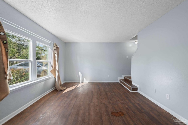 unfurnished living room with plenty of natural light, dark hardwood / wood-style flooring, and a textured ceiling