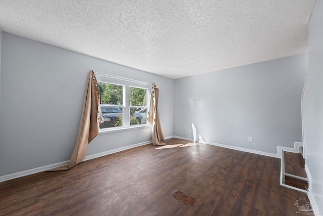 unfurnished room with dark hardwood / wood-style flooring and a textured ceiling