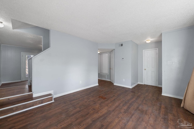 spare room featuring a textured ceiling and dark hardwood / wood-style floors