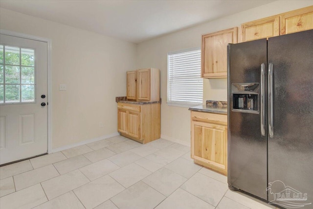 kitchen featuring light brown cabinets, black fridge with ice dispenser, and light tile patterned flooring