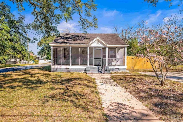 bungalow featuring a front lawn, crawl space, fence, and a sunroom