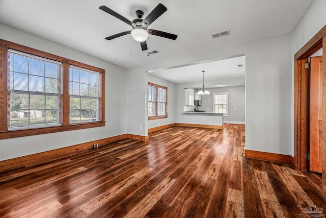 unfurnished living room with a healthy amount of sunlight, visible vents, and dark wood finished floors