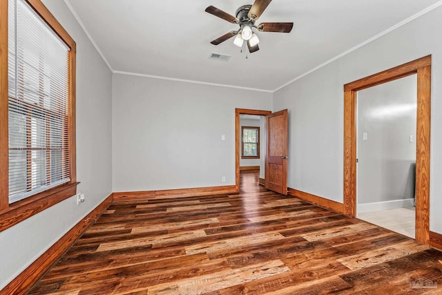 empty room with baseboards, visible vents, a ceiling fan, ornamental molding, and wood finished floors