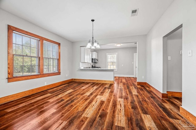 interior space featuring dark wood-style floors, baseboards, visible vents, and a notable chandelier