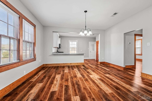 unfurnished living room featuring baseboards, visible vents, dark wood finished floors, and a chandelier