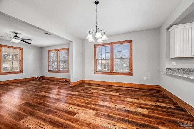 unfurnished dining area with dark wood-style flooring, visible vents, baseboards, and ceiling fan with notable chandelier