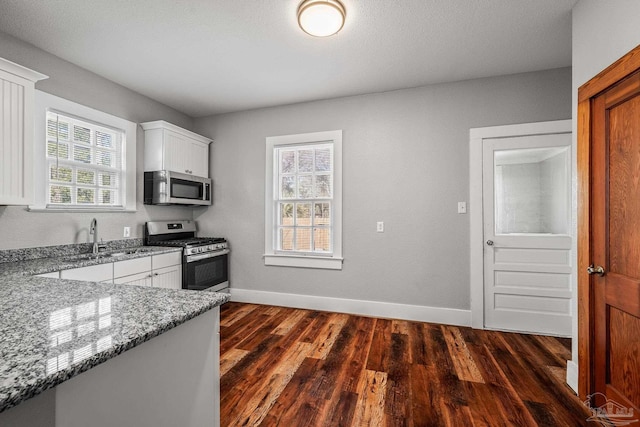 kitchen featuring baseboards, stainless steel appliances, dark wood-style flooring, and light stone countertops