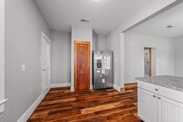 kitchen featuring light stone counters, dark wood-style flooring, visible vents, and stainless steel refrigerator with ice dispenser