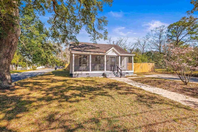 view of front facade featuring a front lawn, crawl space, fence, and a sunroom