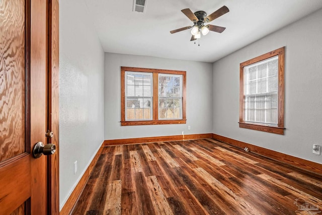 spare room with plenty of natural light, wood finished floors, visible vents, and baseboards