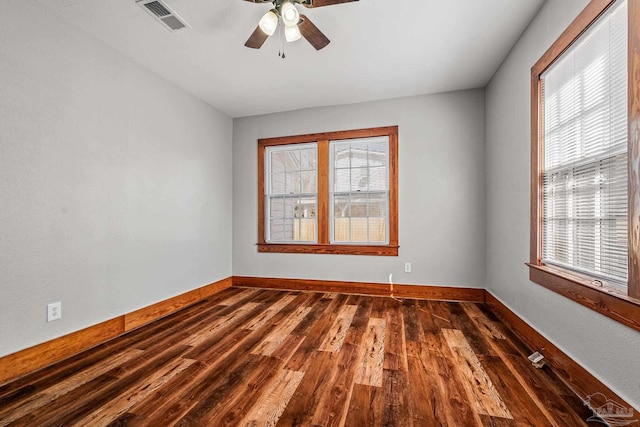 unfurnished room featuring baseboards, plenty of natural light, visible vents, and dark wood-style flooring