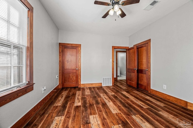 unfurnished bedroom featuring visible vents, dark wood finished floors, baseboards, and ceiling fan