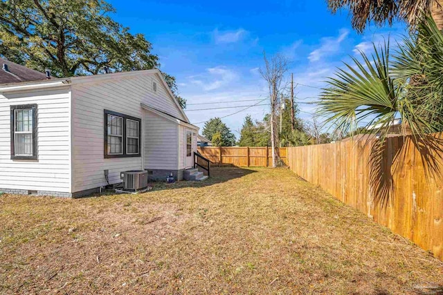 view of yard featuring central air condition unit, a fenced backyard, and entry steps