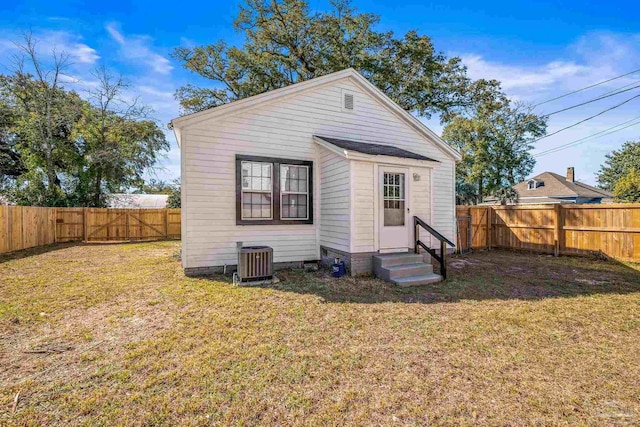 rear view of property with entry steps, a fenced backyard, central AC unit, and a lawn