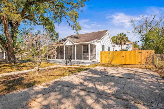 view of front of home featuring a sunroom, crawl space, fence, a gate, and driveway