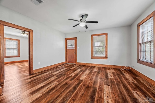 unfurnished living room with a wealth of natural light, visible vents, baseboards, and wood finished floors