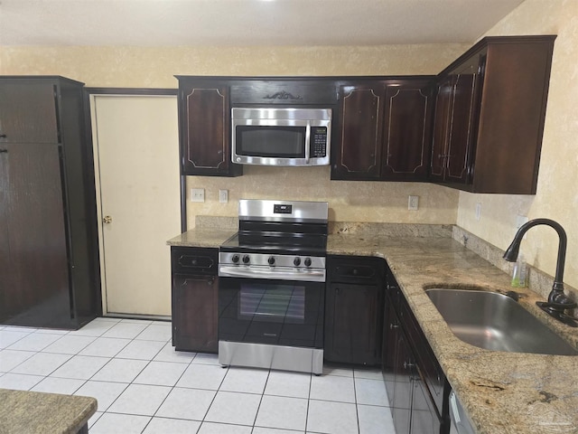 3285 Fairview Dr, Crestview, FL 32539 - kitchen with stainless steel appliances, dark brown cabinets, a sink, light stone counters, and light tile patterned floors