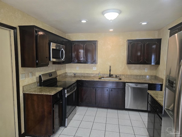 3285 Fairview Dr, Crestview, FL 32539 - kitchen with stainless steel appliances, dark brown cabinets, a sink, a textured wall, and light tile patterned floors