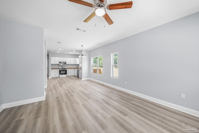 unfurnished living room with ceiling fan with notable chandelier and light wood-type flooring