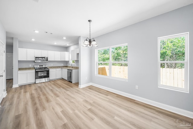 kitchen with decorative light fixtures, white cabinetry, sink, a notable chandelier, and stainless steel appliances