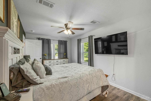 bedroom featuring dark hardwood / wood-style floors, ceiling fan, and a textured ceiling