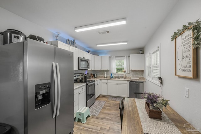 kitchen featuring white cabinetry, light hardwood / wood-style flooring, tasteful backsplash, stainless steel appliances, and sink