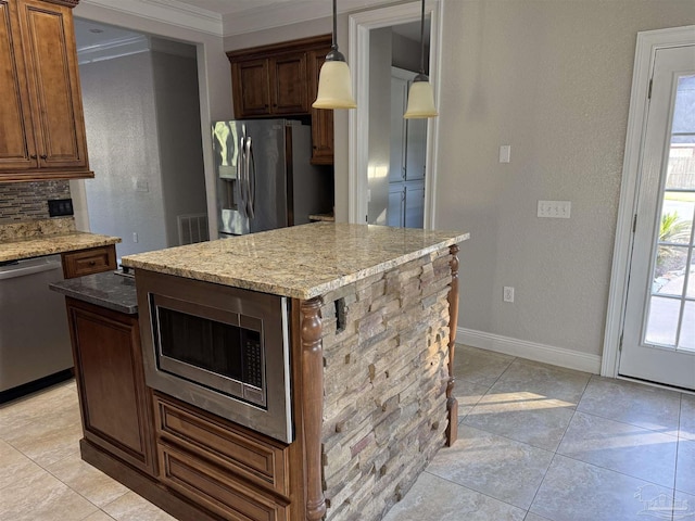 kitchen with a kitchen island, light stone counters, stainless steel appliances, and hanging light fixtures