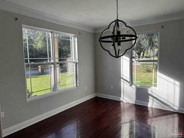 unfurnished dining area featuring a chandelier, a textured ceiling, crown molding, and dark wood-type flooring