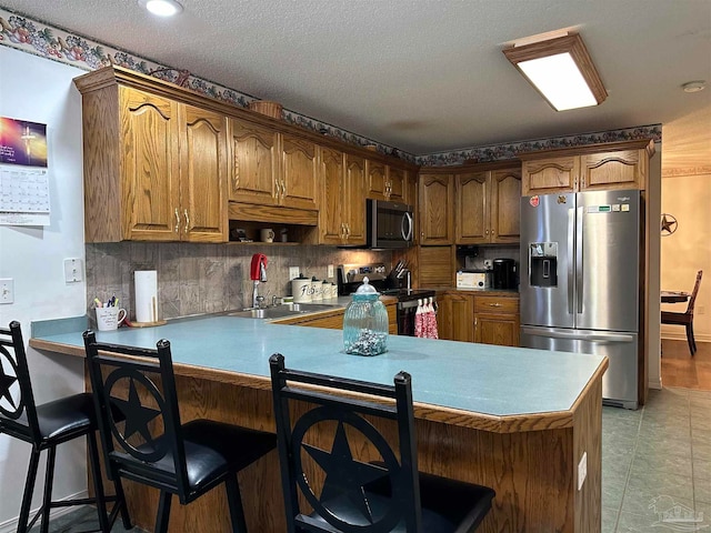 kitchen with appliances with stainless steel finishes, a breakfast bar, sink, kitchen peninsula, and light tile patterned floors