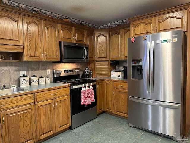 kitchen featuring sink, decorative backsplash, tile patterned flooring, and stainless steel appliances