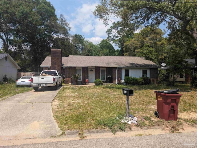 single story home featuring concrete driveway, brick siding, a chimney, and a front lawn